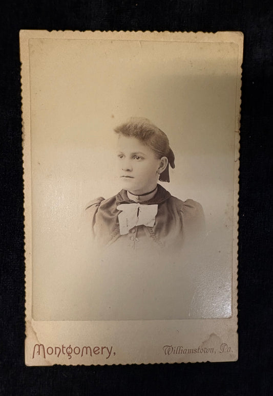 Vintage sepia-toned portrait of a young girl with 'Montgomery' and 'Williamsport, Pa.' text on a dark background.