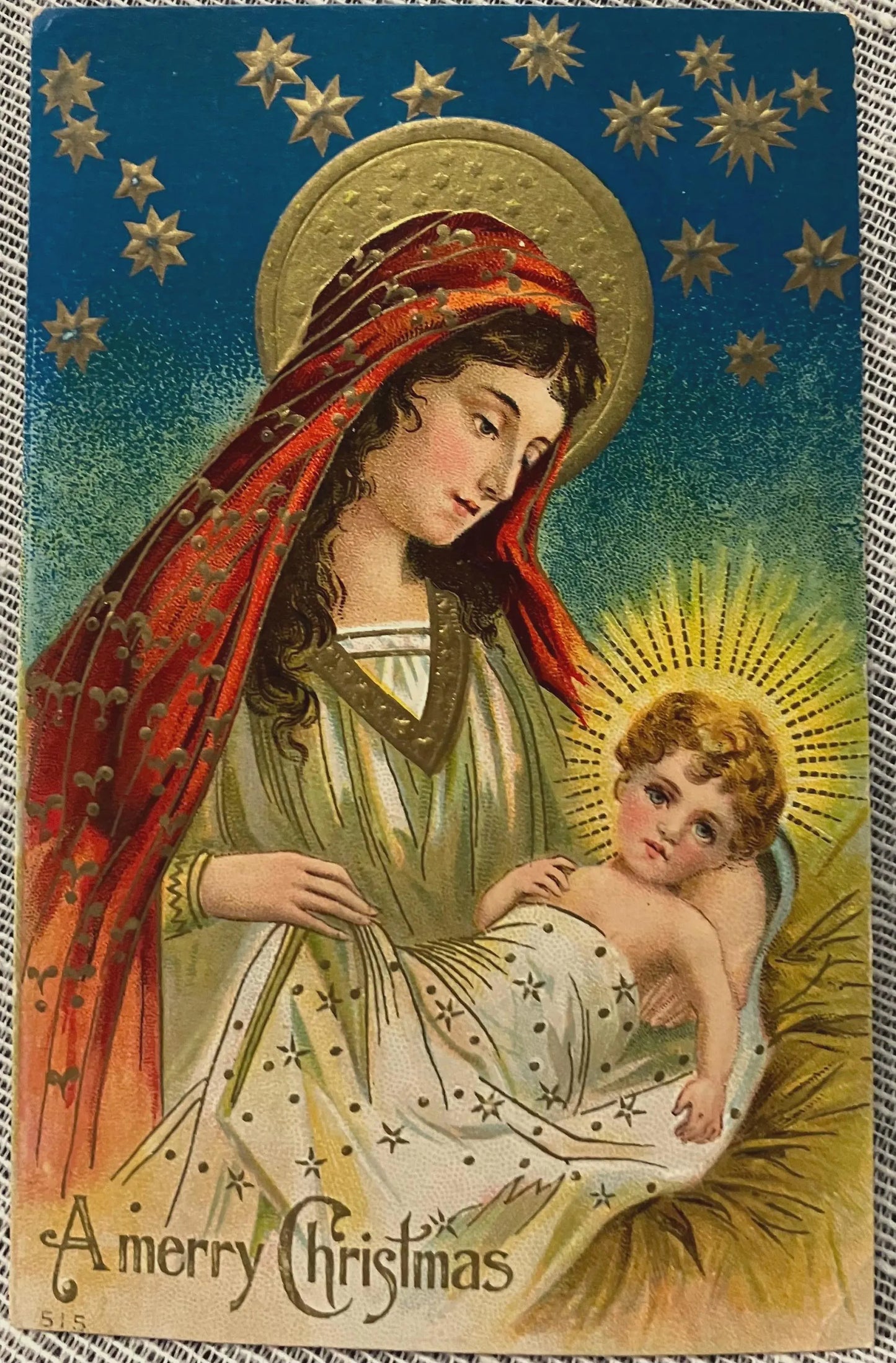 Vintage-style Christmas card with Mary holding baby Jesus, surrounded by stars.