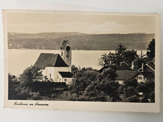 Vintage black and white photo of a church and surrounding buildings by a lake