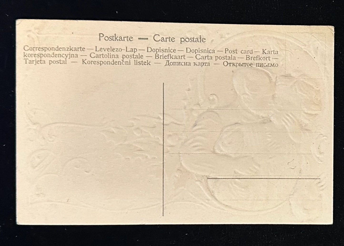 Back of a postcard with embossed design and text in multiple languages.
