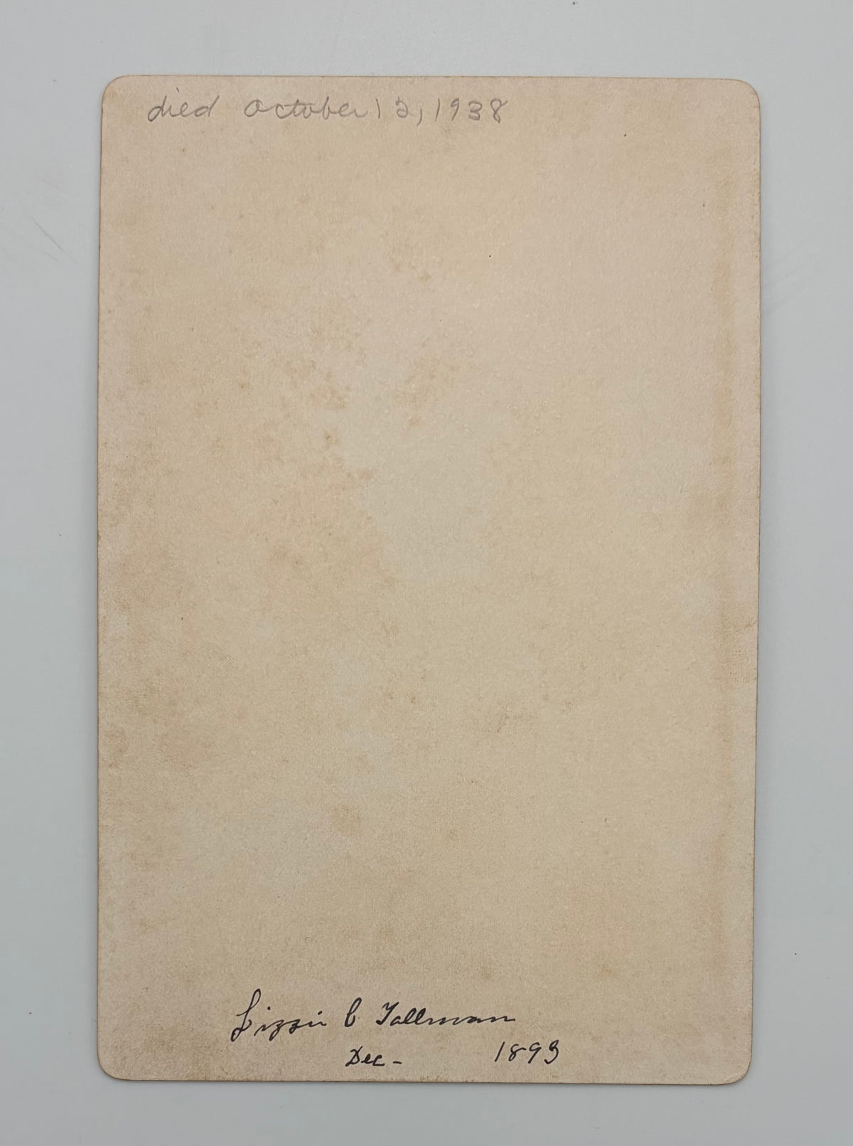 A vintage beige paper card or label with handwritten text at the top reading 'died October 12, 1938'