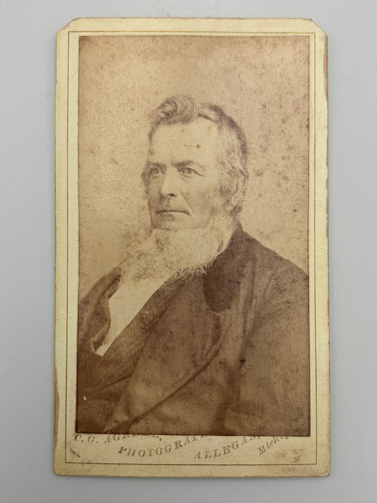 A vintage carte de visite portrait photograph print of an elderly bearded man, mounted on a cream-colored card with printed text at the bottom.