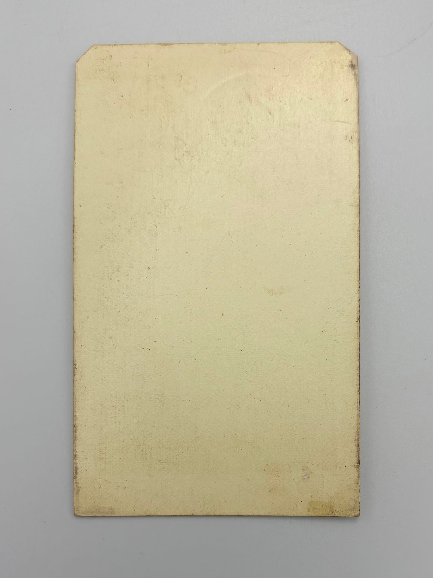 A blank, aged beige rectangular card with a slightly textured surface, photographed flat against a neutral gray background.