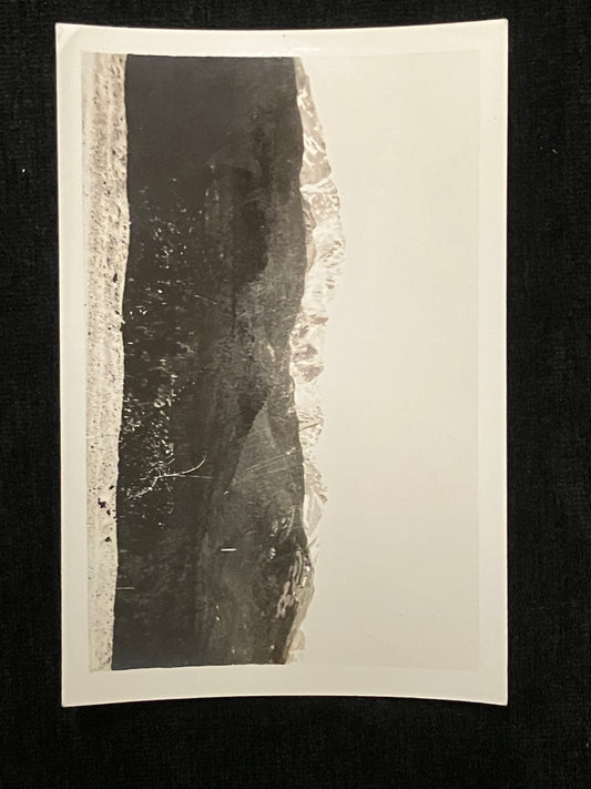 A black and white photographic print mounted with a white paper border, displayed against a dark black background.