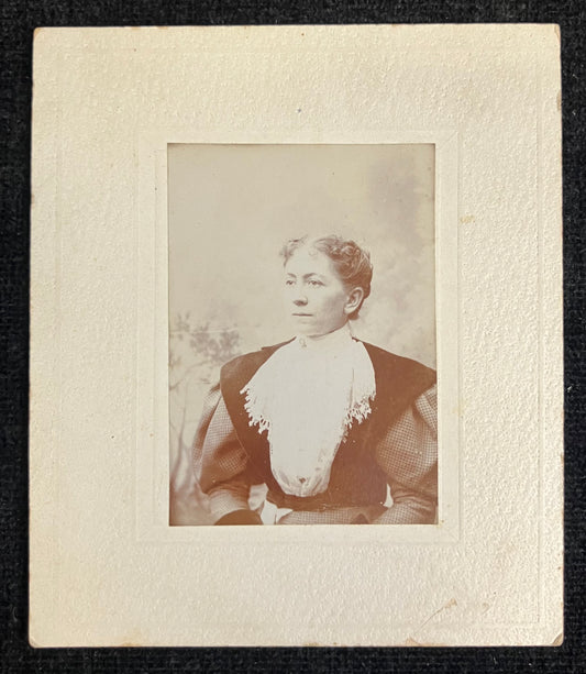 Vintage photograph of a woman with a decorative collar, framed by a textured border.