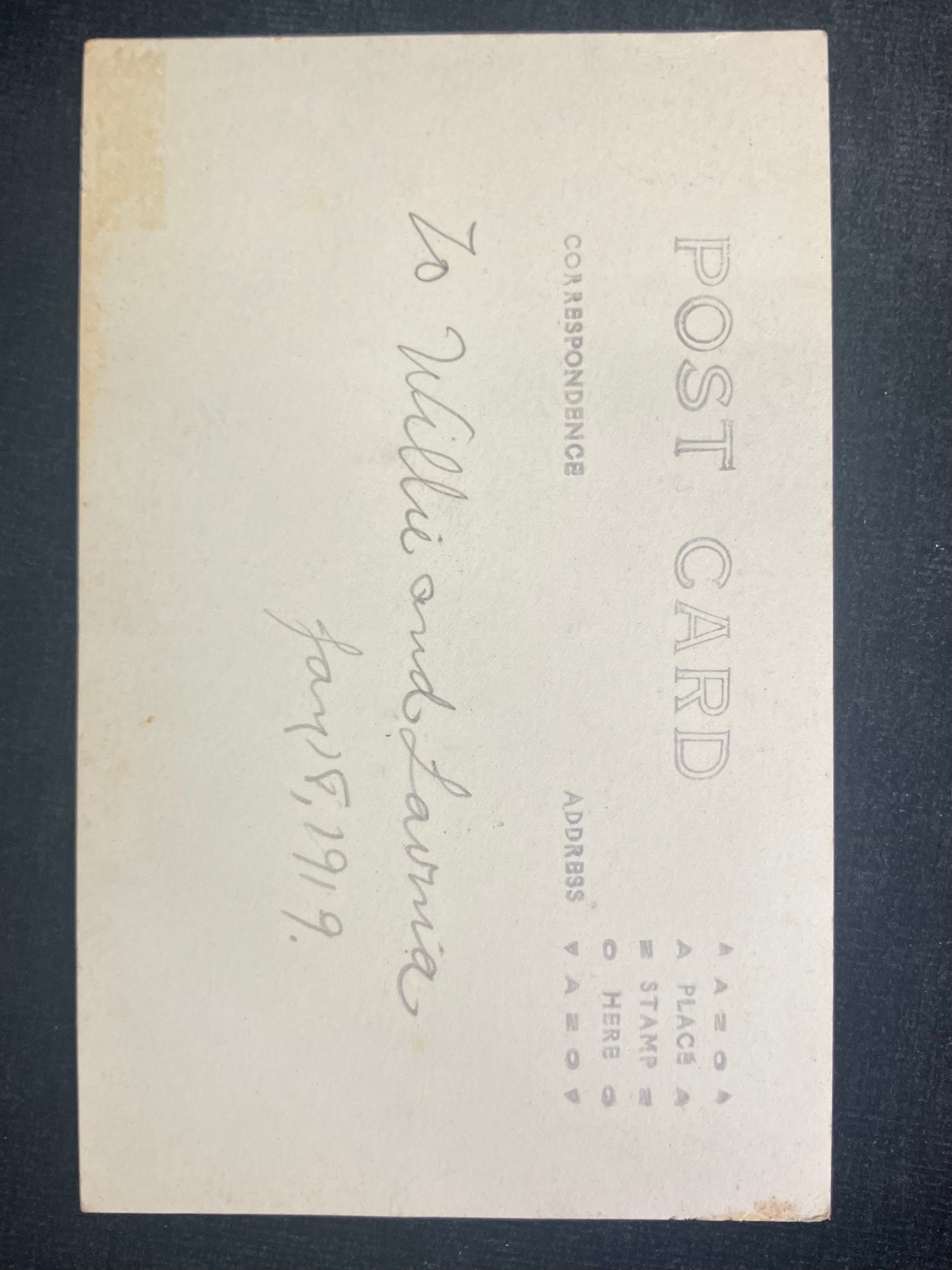 Back of a postcard with text and a signature on a dark background
