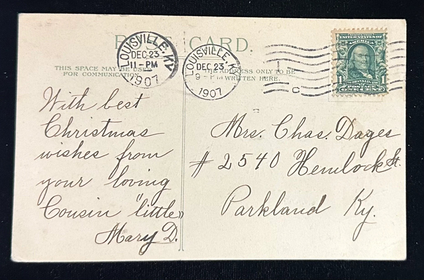 Vintage Christmas postcard with stamps and cursive writing, featuring a Christmas stamp on the back.