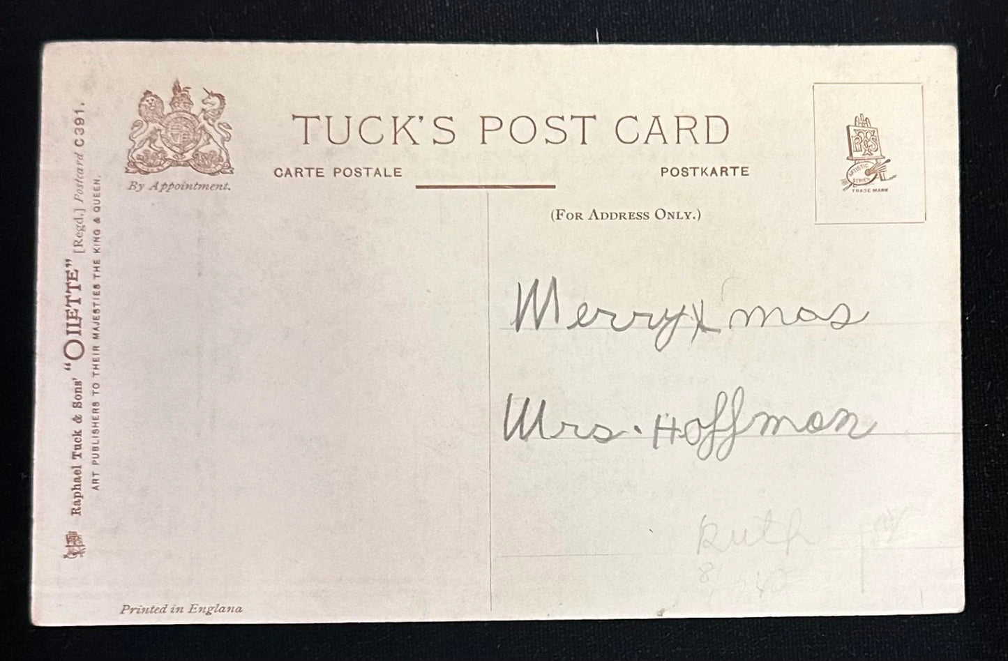 Vintage Tuck's postcard with text and a signature on a black background