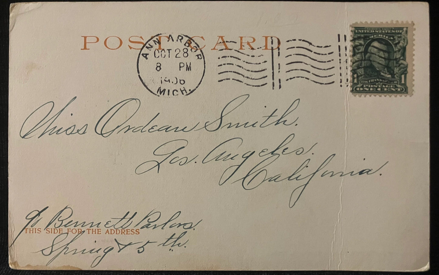 Vintage postcard with postage stamp and handwritten text, featuring a green stamp on a light brown background.