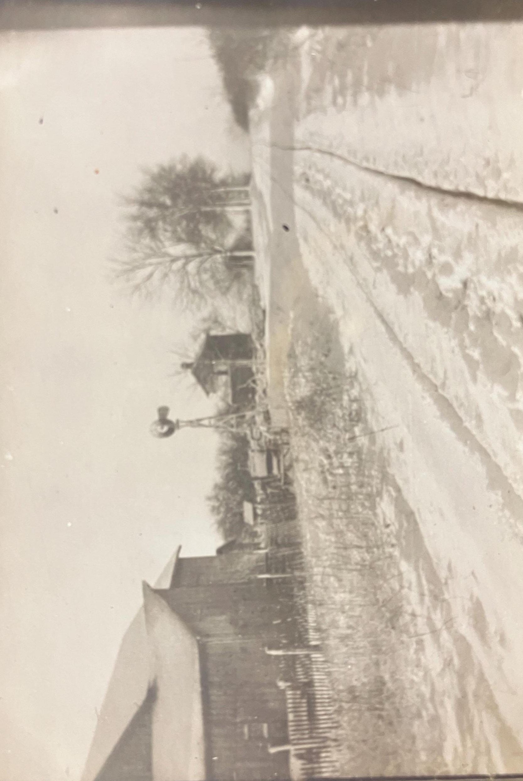 A black and white photo of a postcard showing a Michigan country road scene with a farm house, windmill, and barns covered in fresh fallen snow, dated March 13, 1911.