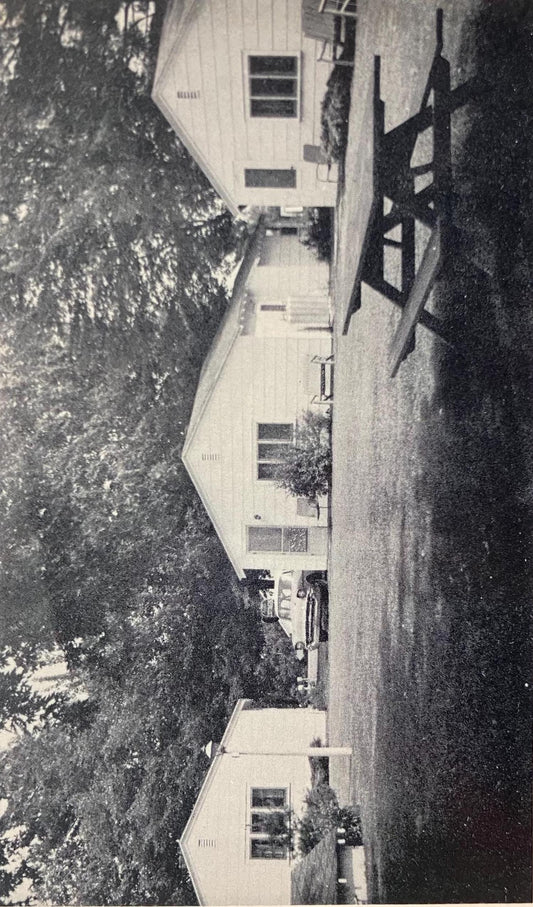 Black and white photo of a house with trees and a front lawn