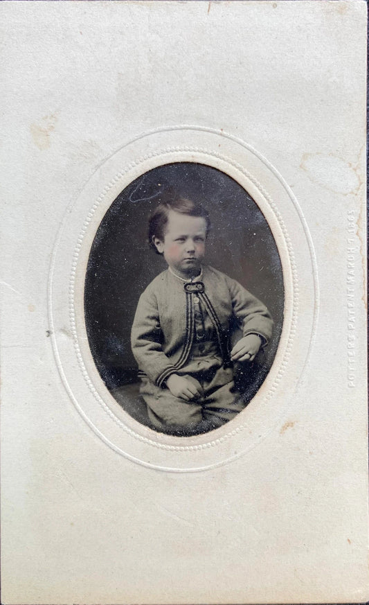 Vintage photograph of a young boy in formal attire on a textured blue background