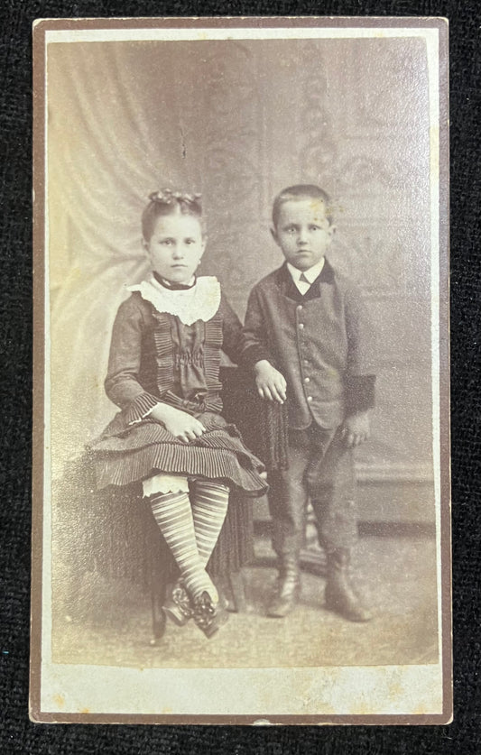 Vintage photograph of two children in formal attire sitting together.