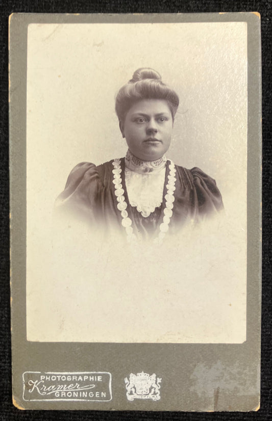 Vintage black and white portrait of a woman with jewelry, framed by a border with text.