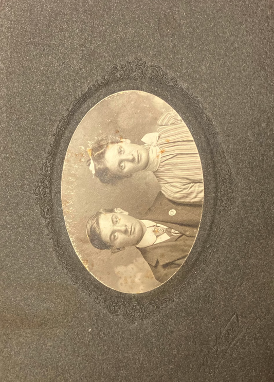 Vintage sepia-toned portrait of a couple in an oval frame on a textured brown background