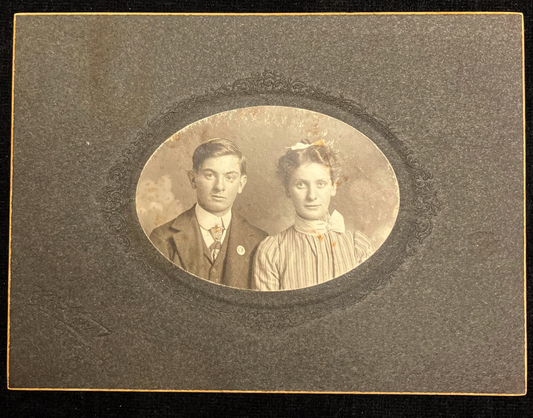 Vintage sepia-toned portrait of a man and woman in an oval frame.