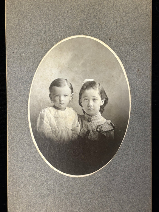 Vintage black and white portrait of two young girls in formal attire.
