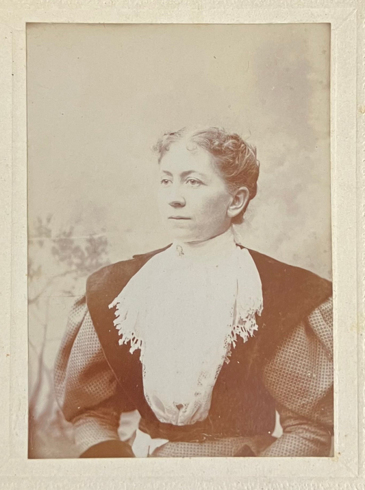 Vintage sepia-toned portrait of a woman wearing a dark dress with a white lace collar.