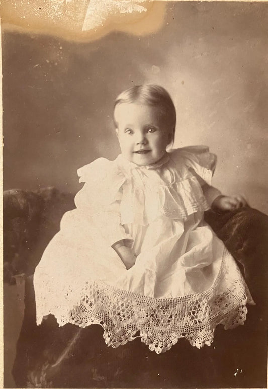 Vintage black and white photograph of a child in a lace dress against a plain background