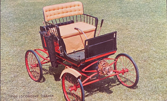 Vintage red and black steamer car on a grassy background