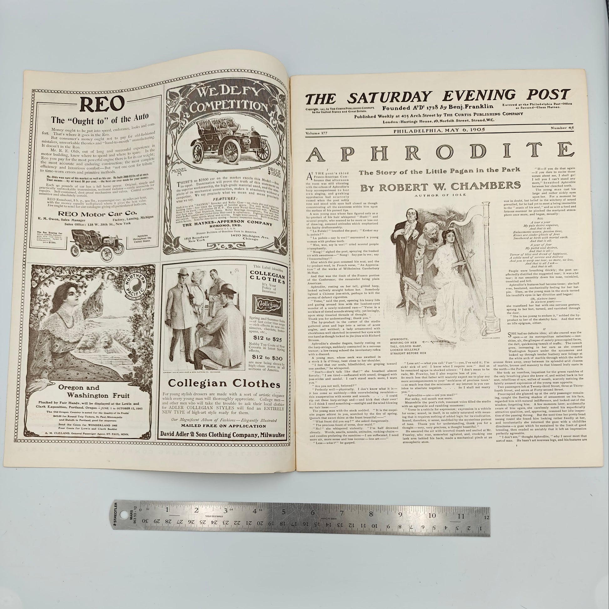 Open newspaper with visible text and images on a light blue background, with a ruler for scale. Titled "The Picknickers", this magazine features ads for REO Motor Car Co., Baynes-Apperson Co., Oregon and Washington Fruit at Lewis and Clark Exposition, Collegian Clothes by Adler and Sons.