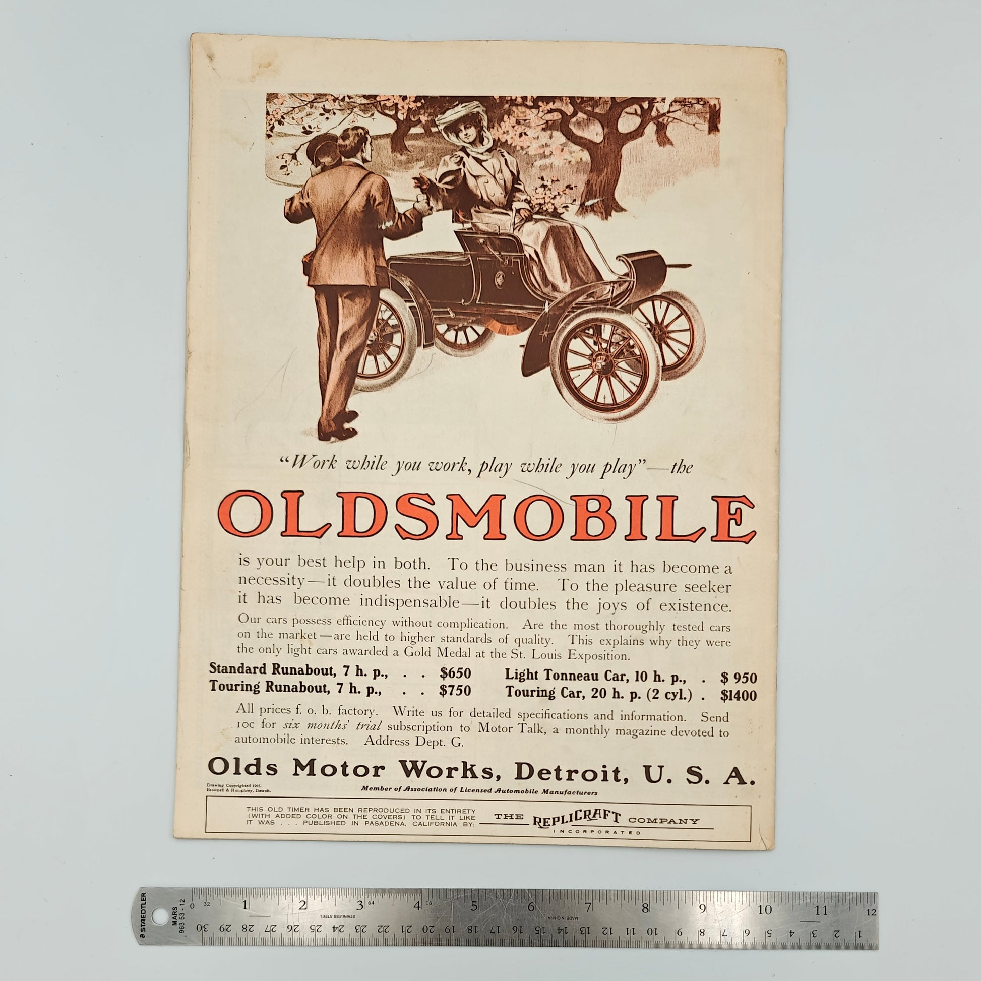 Vintage Oldsmobile advertisement on a white surface with a ruler for scale.