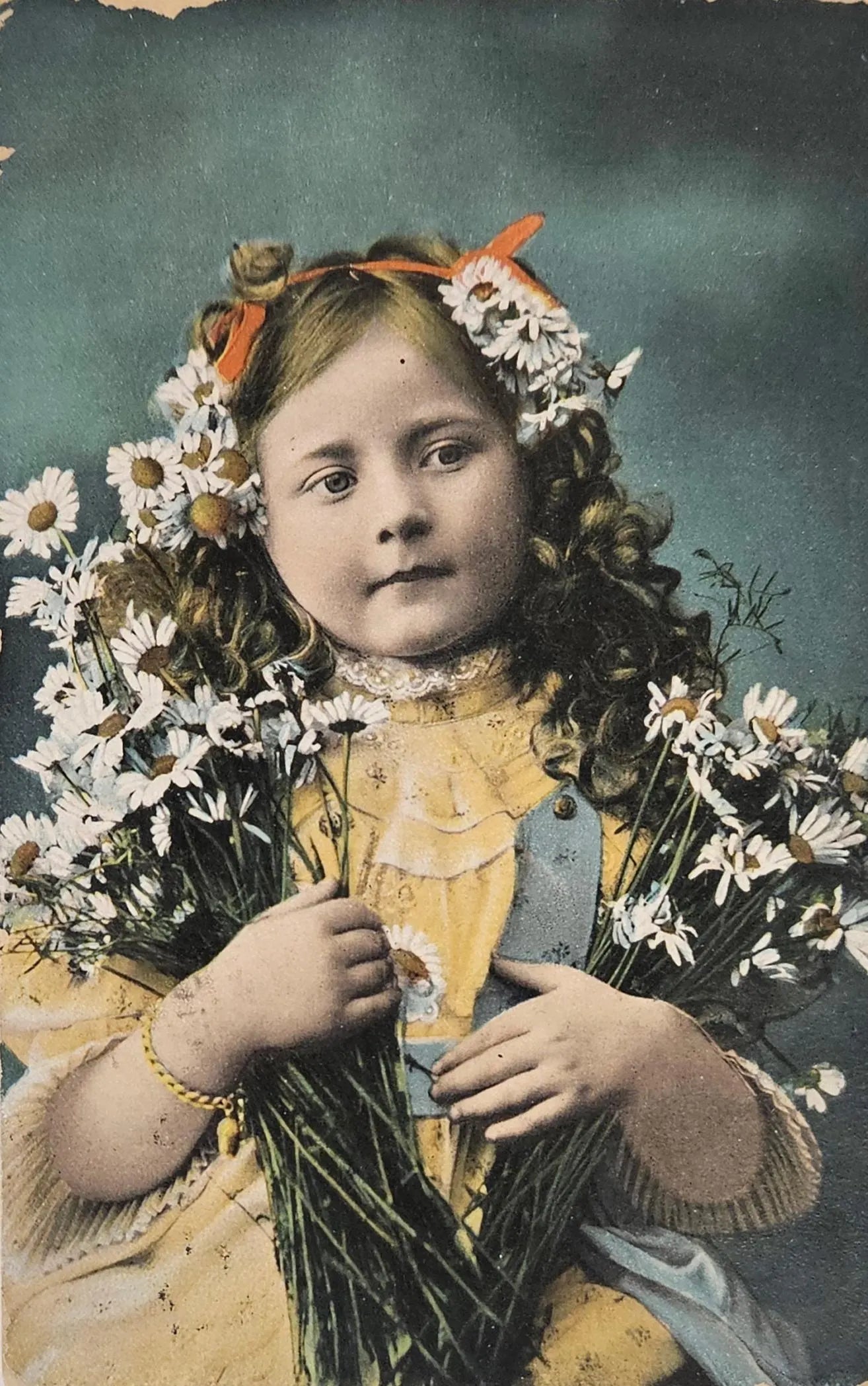 Vintage photograph of a young girl holding flowers against a dark background