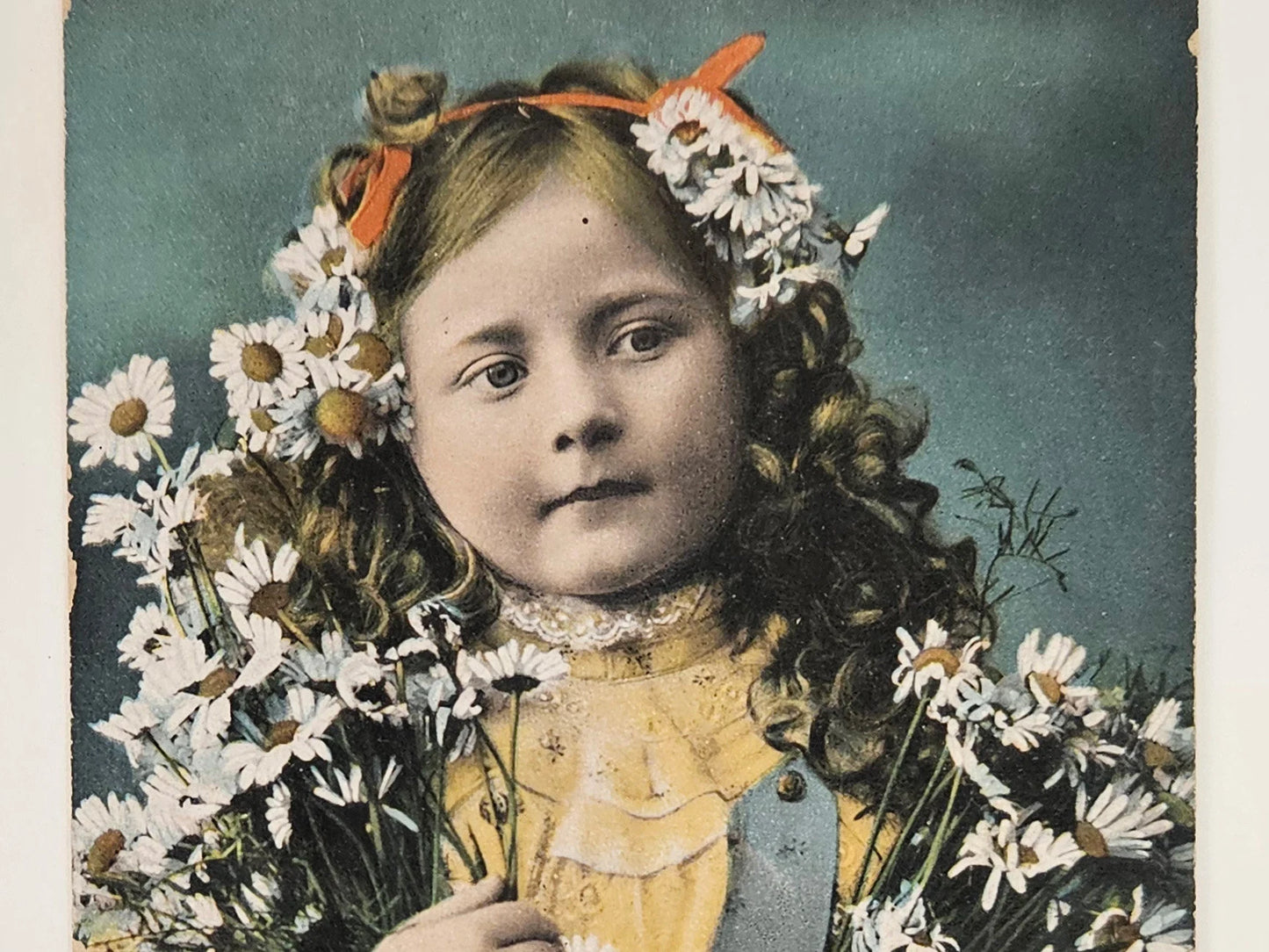 Vintage photograph of a young girl with flowers in her hair and around her shoulders.