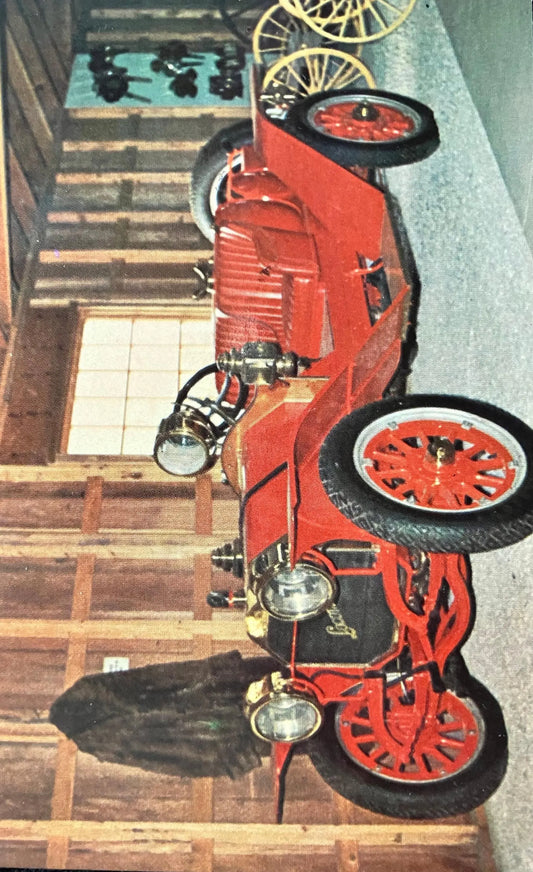 Red vintage fire engine on display indoors with wooden floor and tiled wall.