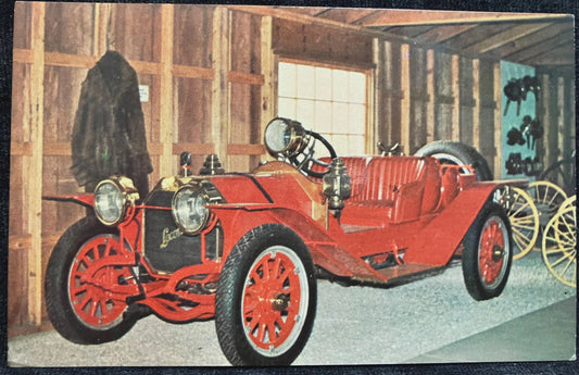 Vintage red car in a showroom with wooden walls and large windows.