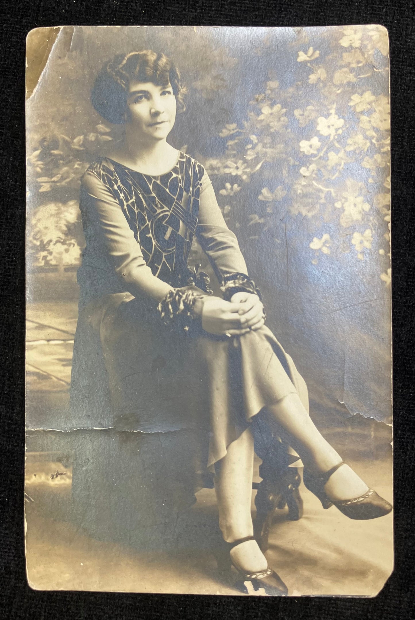 Vintage photograph of a woman sitting outdoors with floral background