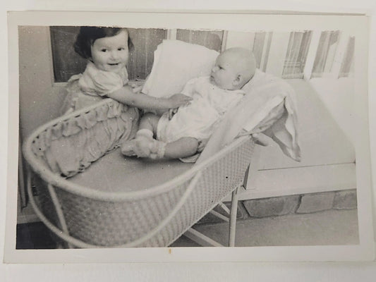 Black and White Photo of Smiling Toddler Meeting Baby Brother in Cradle, 1950s - Classic Family Photo of  Children - LaCrosse Wisconsin