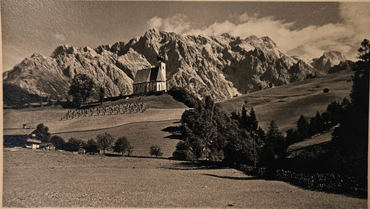 Vintage photograph of a train on a mountain pass with a scenic landscape.