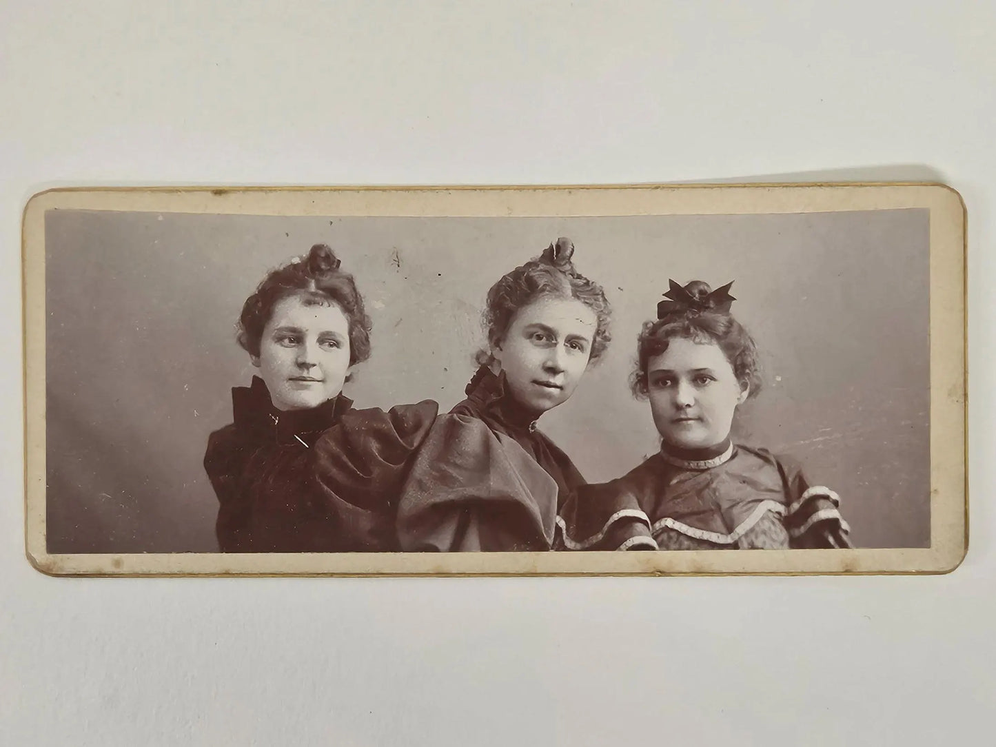 Vintage photograph of three women posing together on a plain background