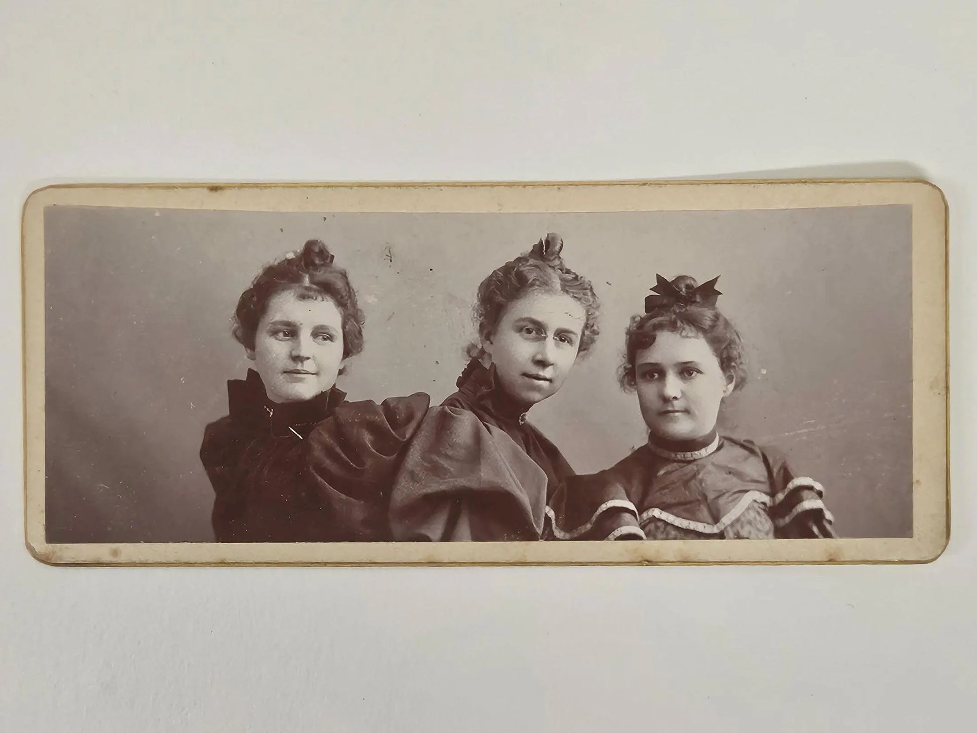 Vintage photograph of three women posing together on a plain background