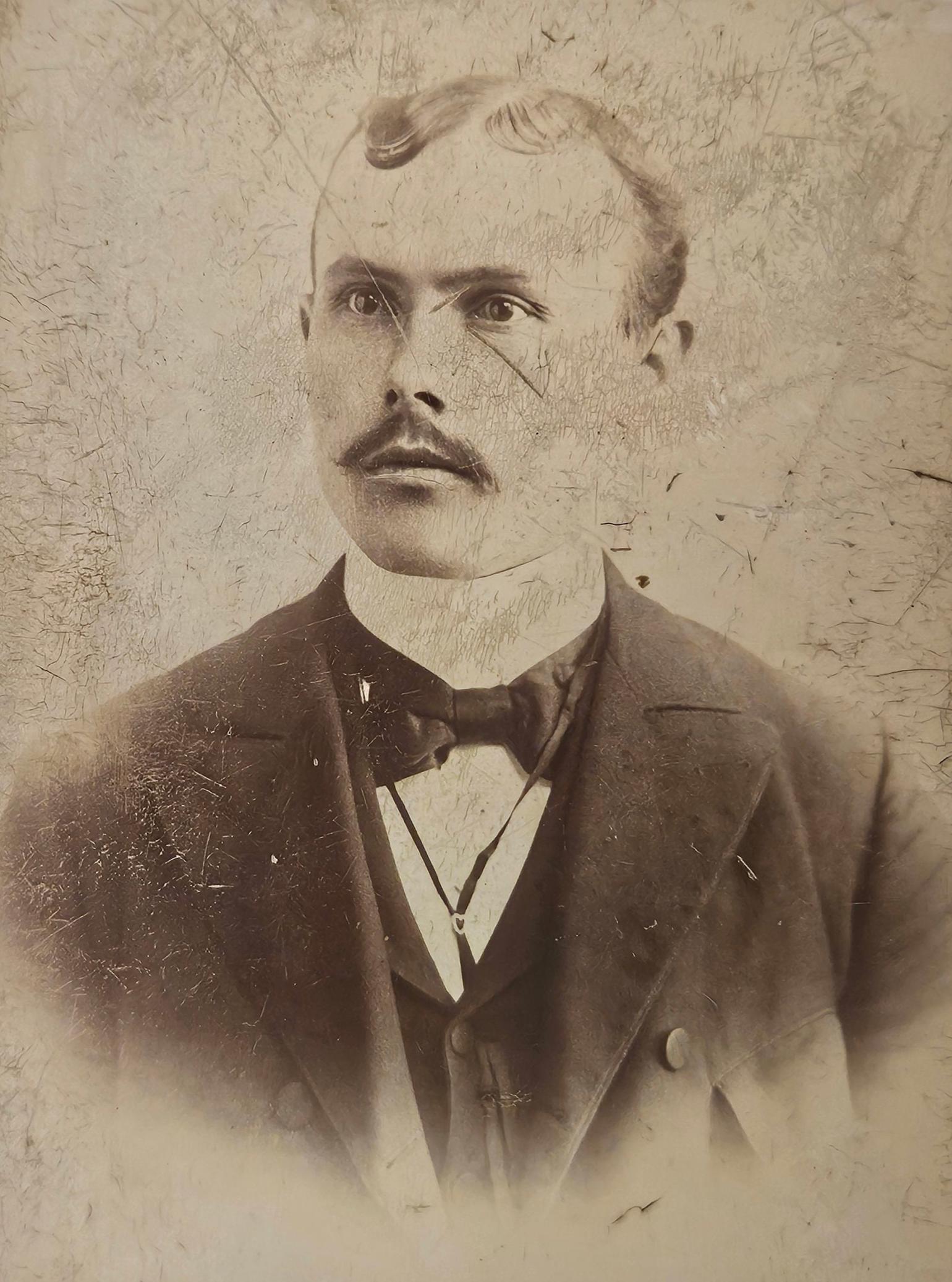 Vintage portrait of a man with a mustache and formal attire against a textured background