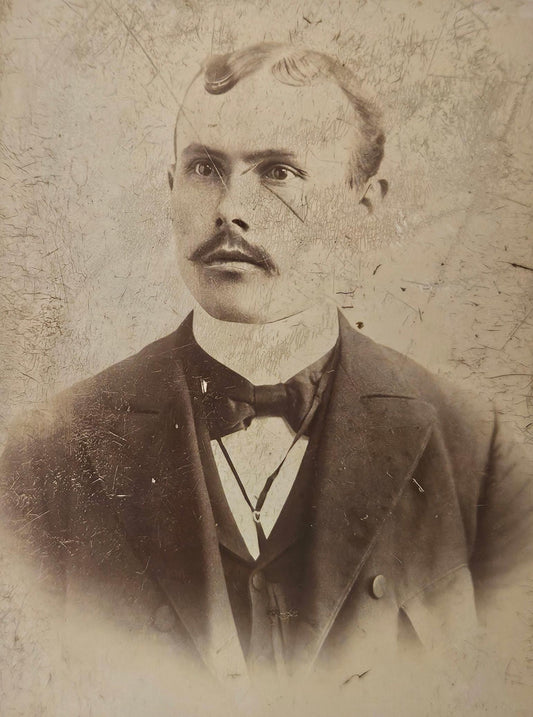 Vintage portrait of a man with a mustache and formal attire against a textured background