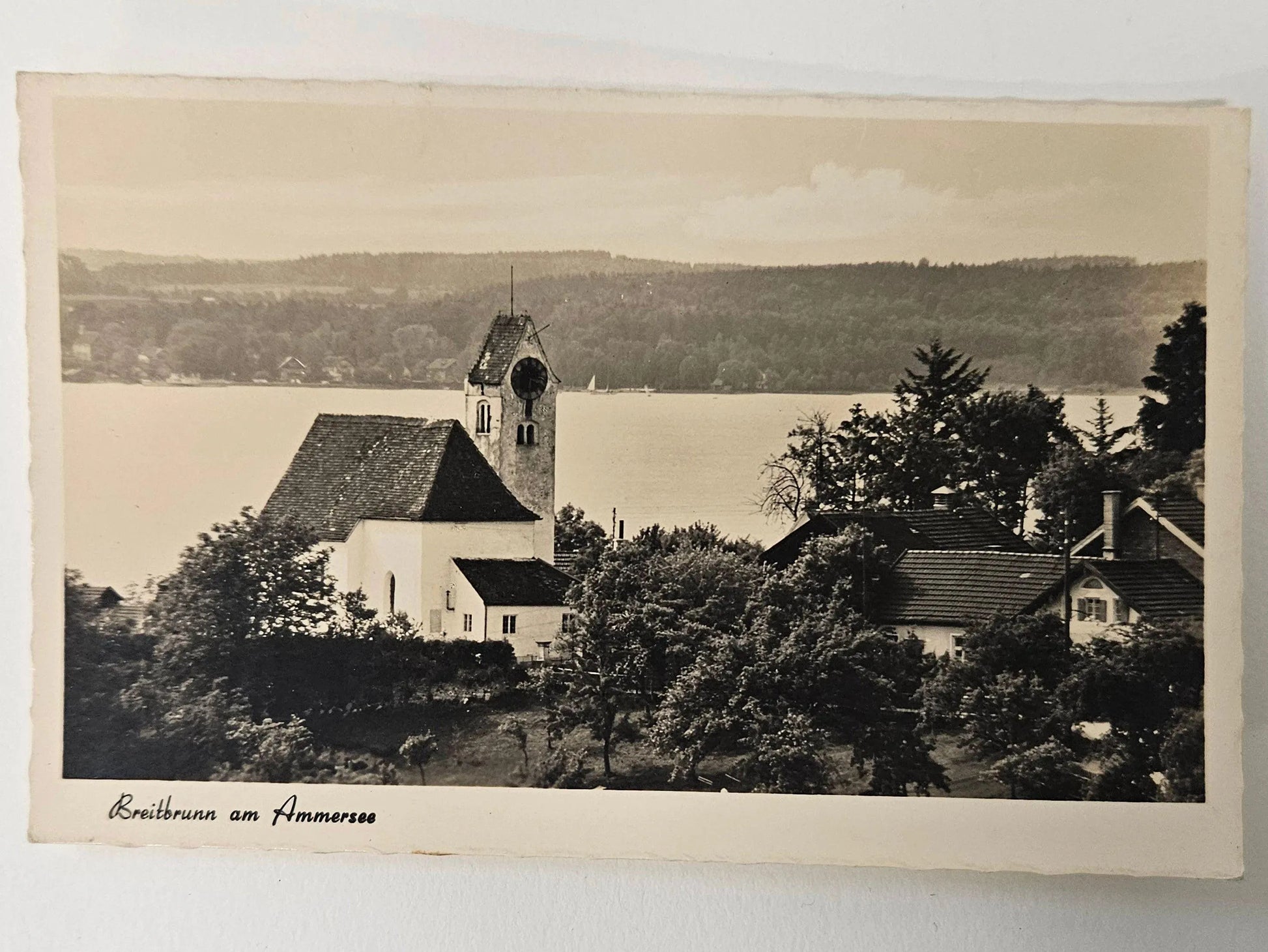 Vintage black and white photo of a church and surrounding buildings by a lake