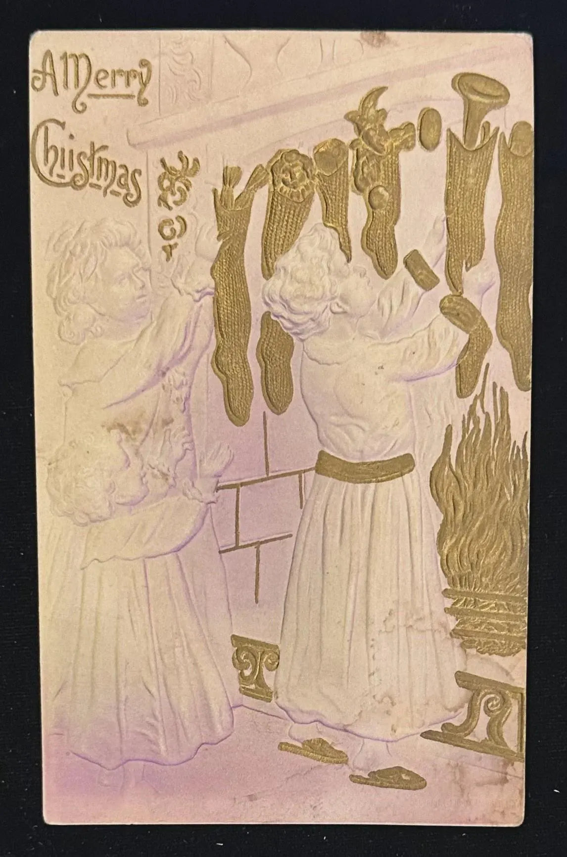Vintage Christmas card with gold illustration of a woman and child by a fireplace.