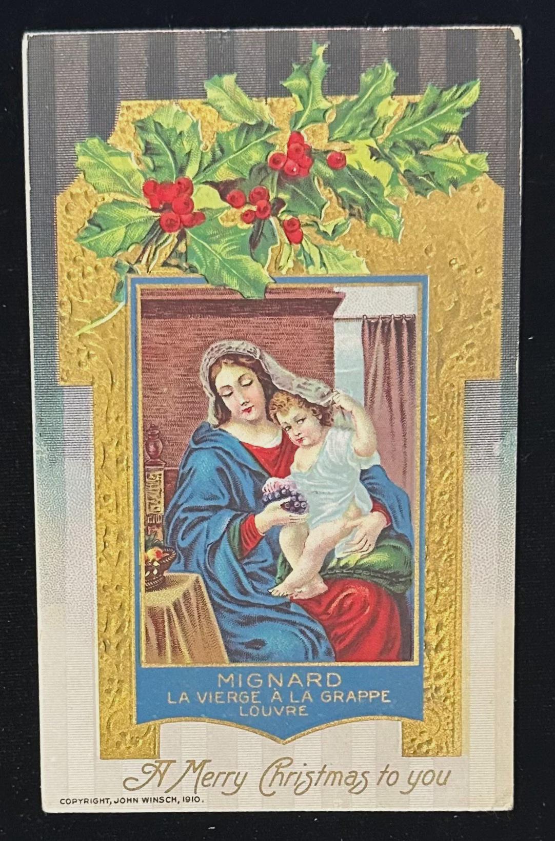 Vintage Christmas card with a depiction of a woman holding a child, surrounded by holly leaves and berries.