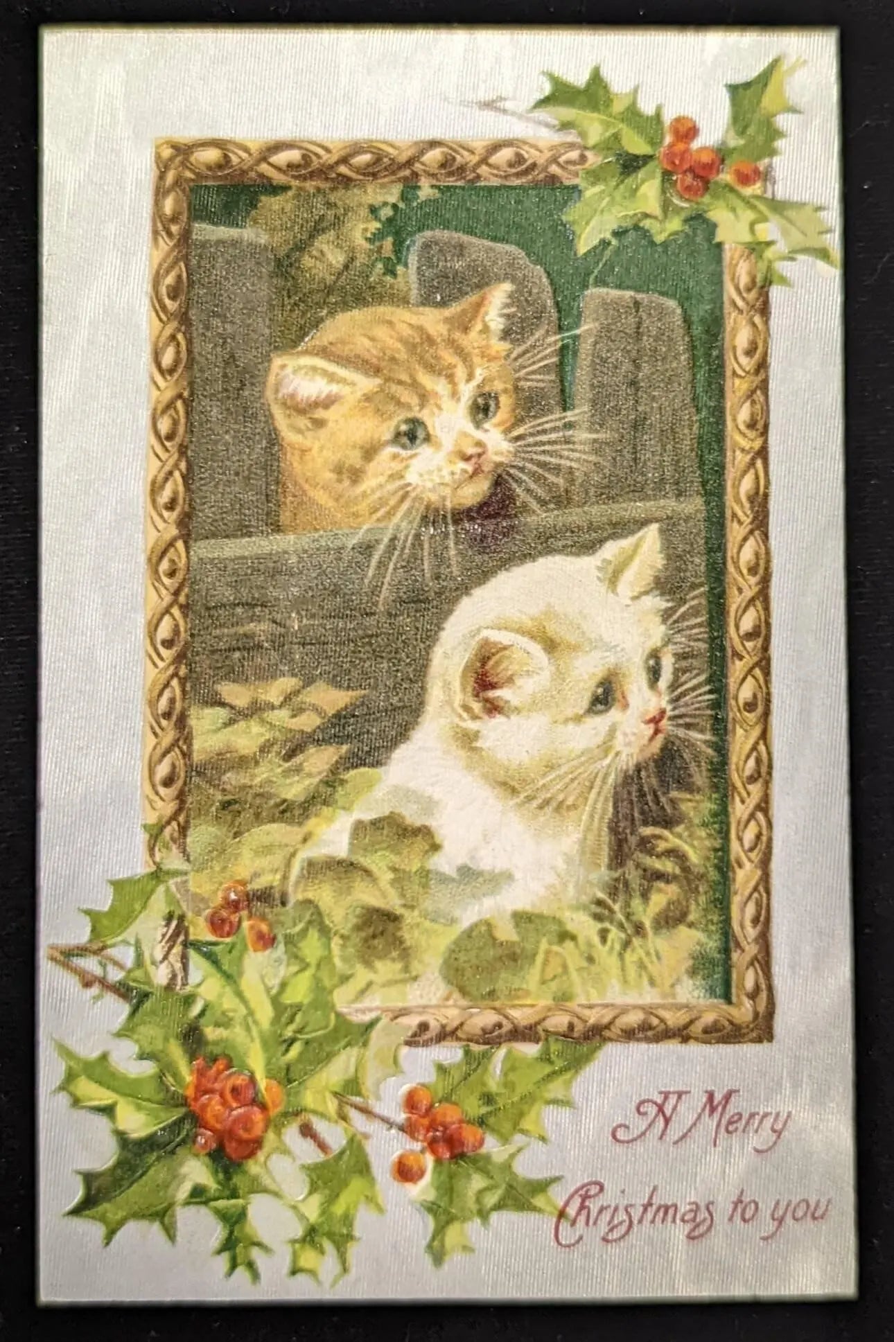 Vintage-style Christmas card with two cats and holly leaves.