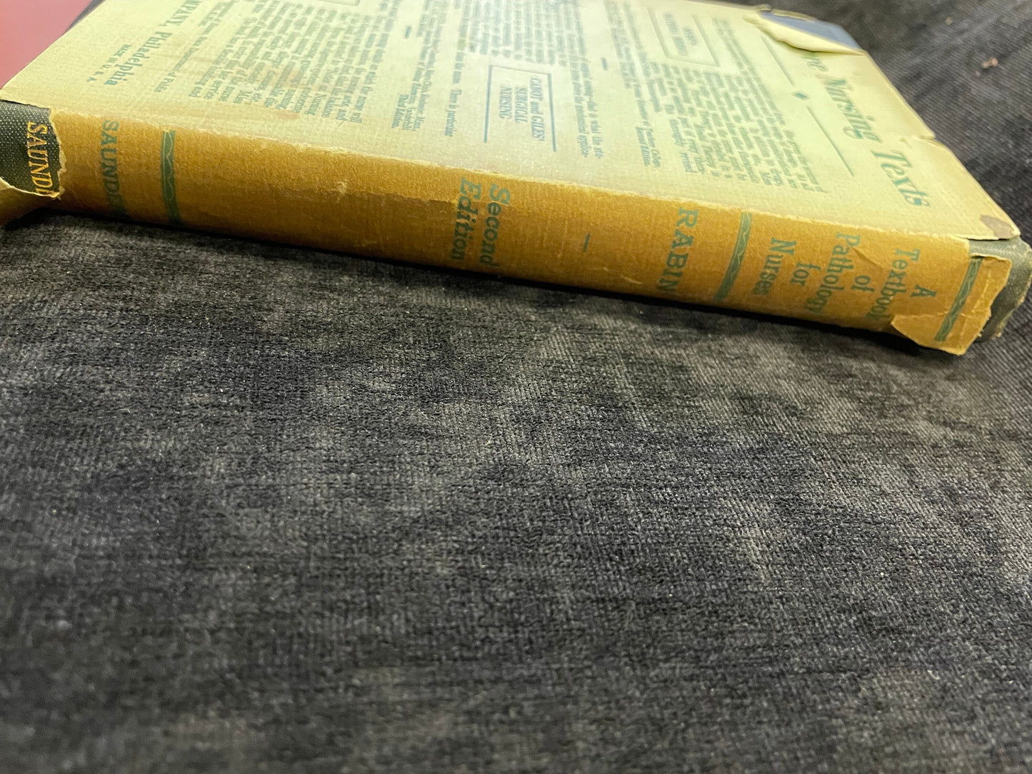 Yellowed book with text on a gray fabric surface