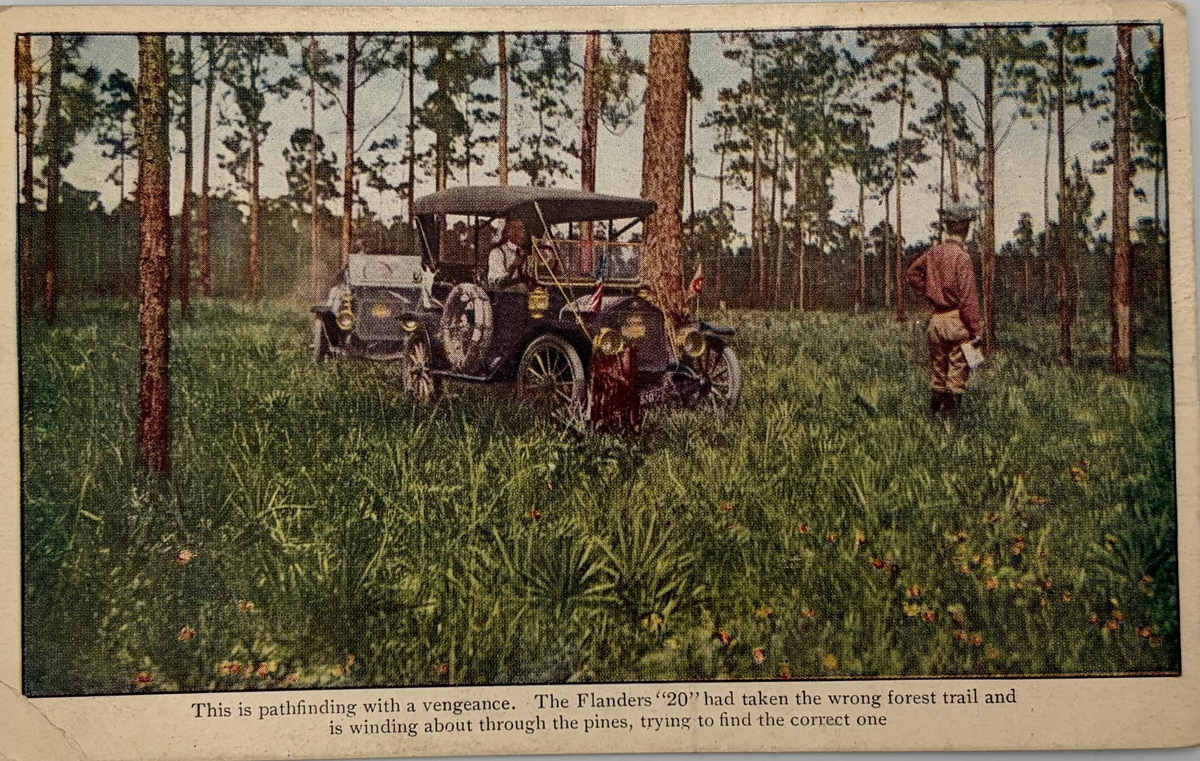 Vintage illustrated postcard or print showing an early car in a forest clearing with a person standing nearby, plus printed caption text along the bottom.