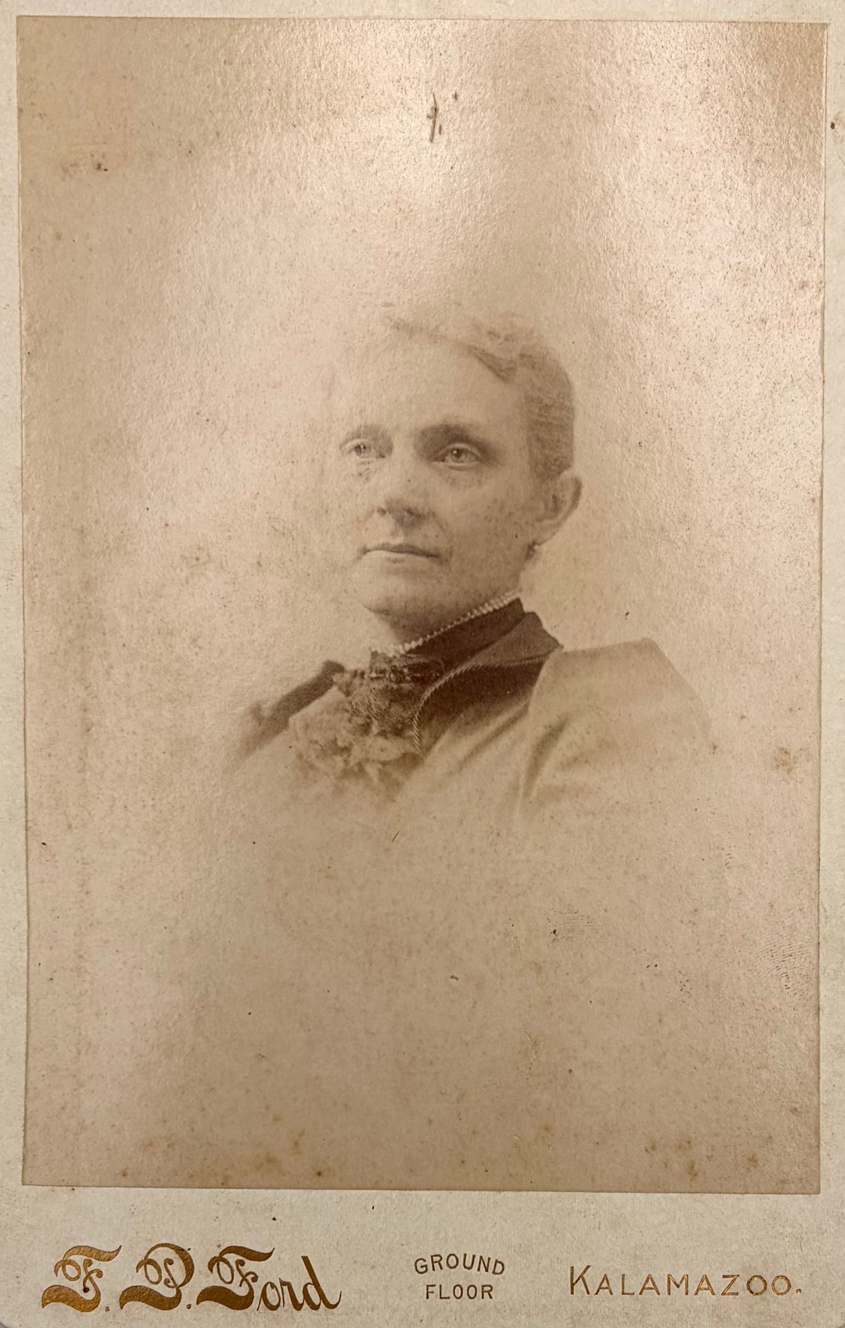 Vintage sepia-toned cabinet portrait of a woman with the text 'F.P. Ford Kalamazoo'