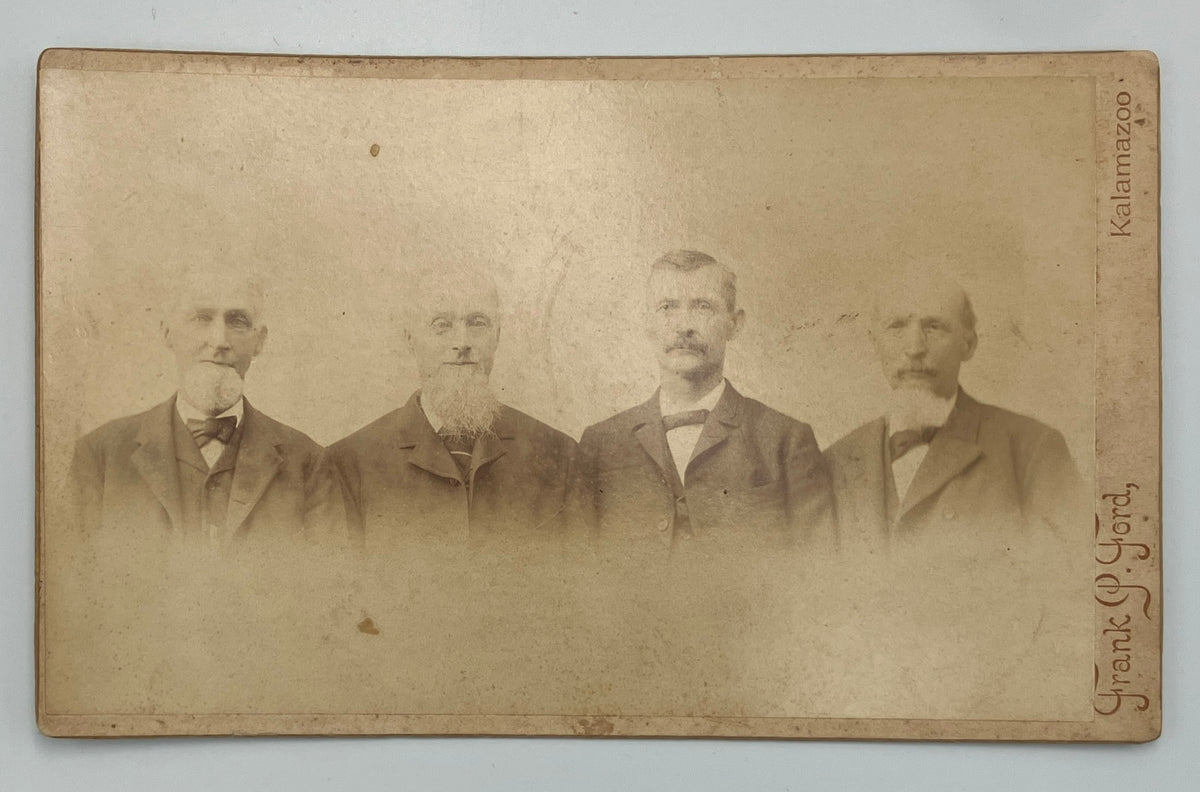An antique sepia-toned cabinet card photograph showing four men in formal suits, with handwritten text along the right edge including 'Kalamazoo' and 'Frank P. Ford'.