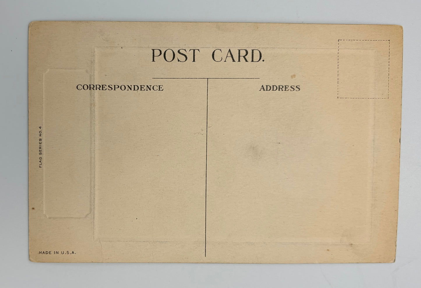 Vintage postcard back with a warm beige aged paper finish, featuring printed black text reading 'POST CARD', address sections, and dashed stamp box outlines on a light gray background.