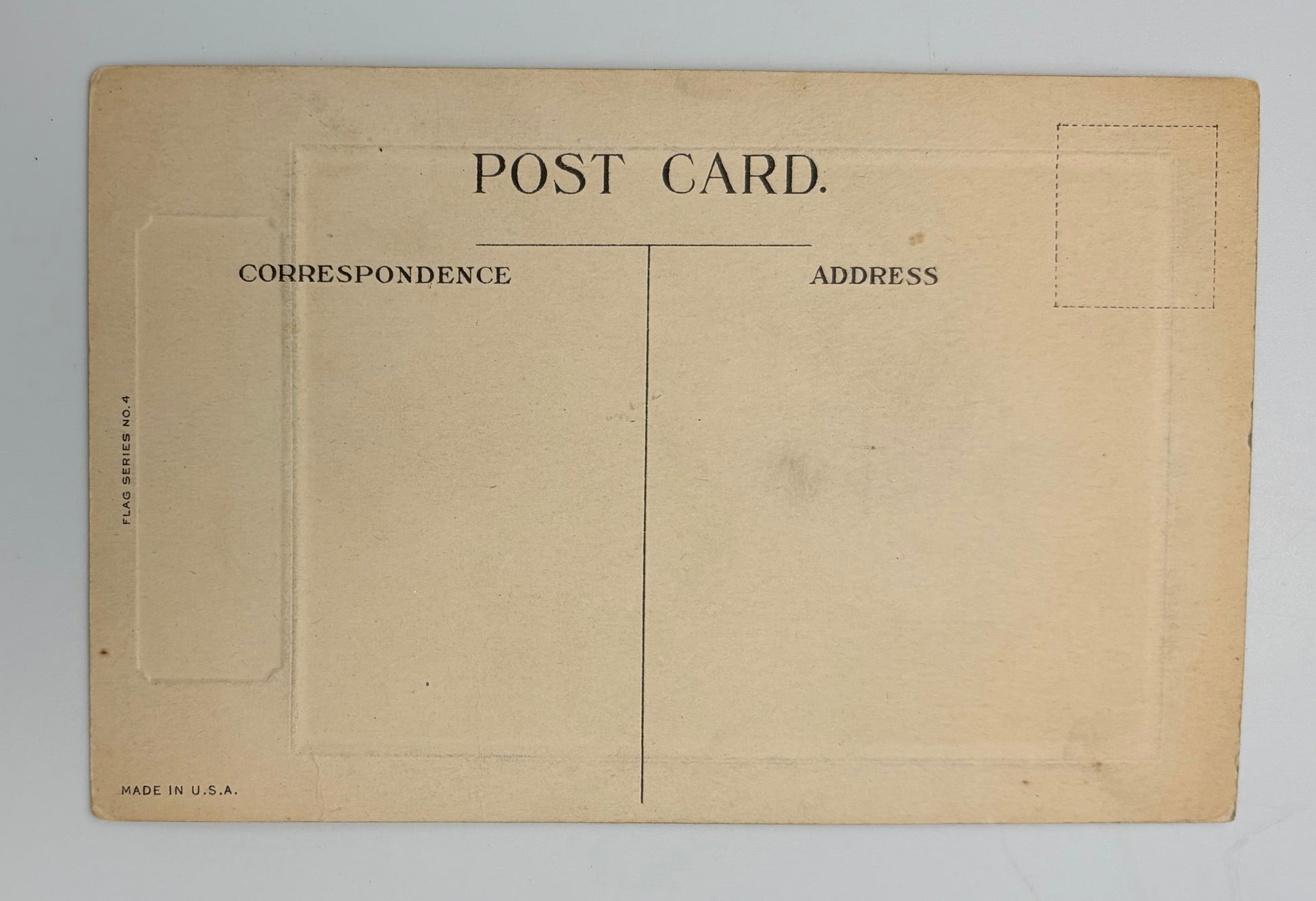 Vintage postcard back with a warm beige aged paper finish, featuring printed black text reading 'POST CARD', address sections, and dashed stamp box outlines on a light gray background.