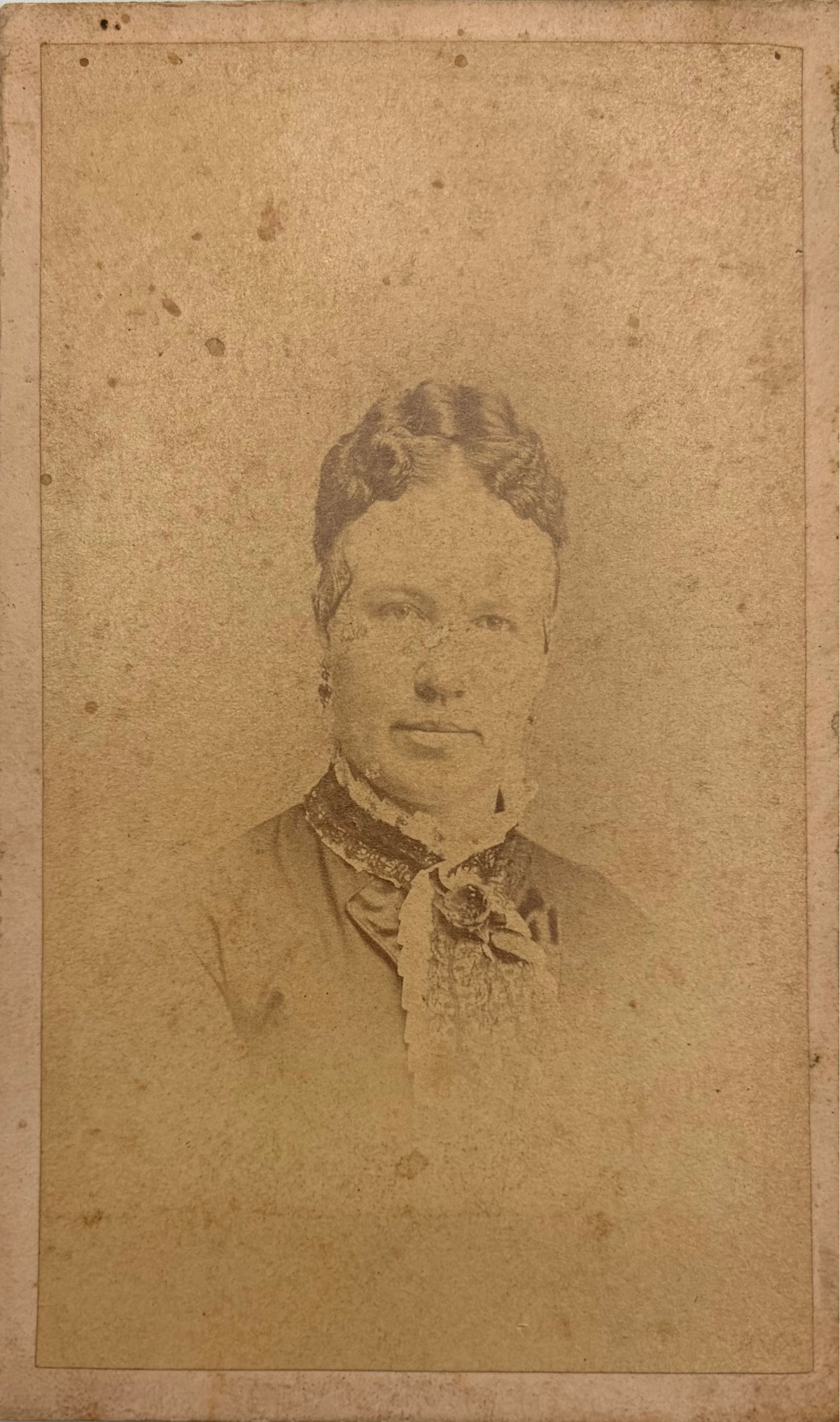 An antique carte de visite portrait card featuring a sepia-toned portrait of a woman, mounted on a light gray background.