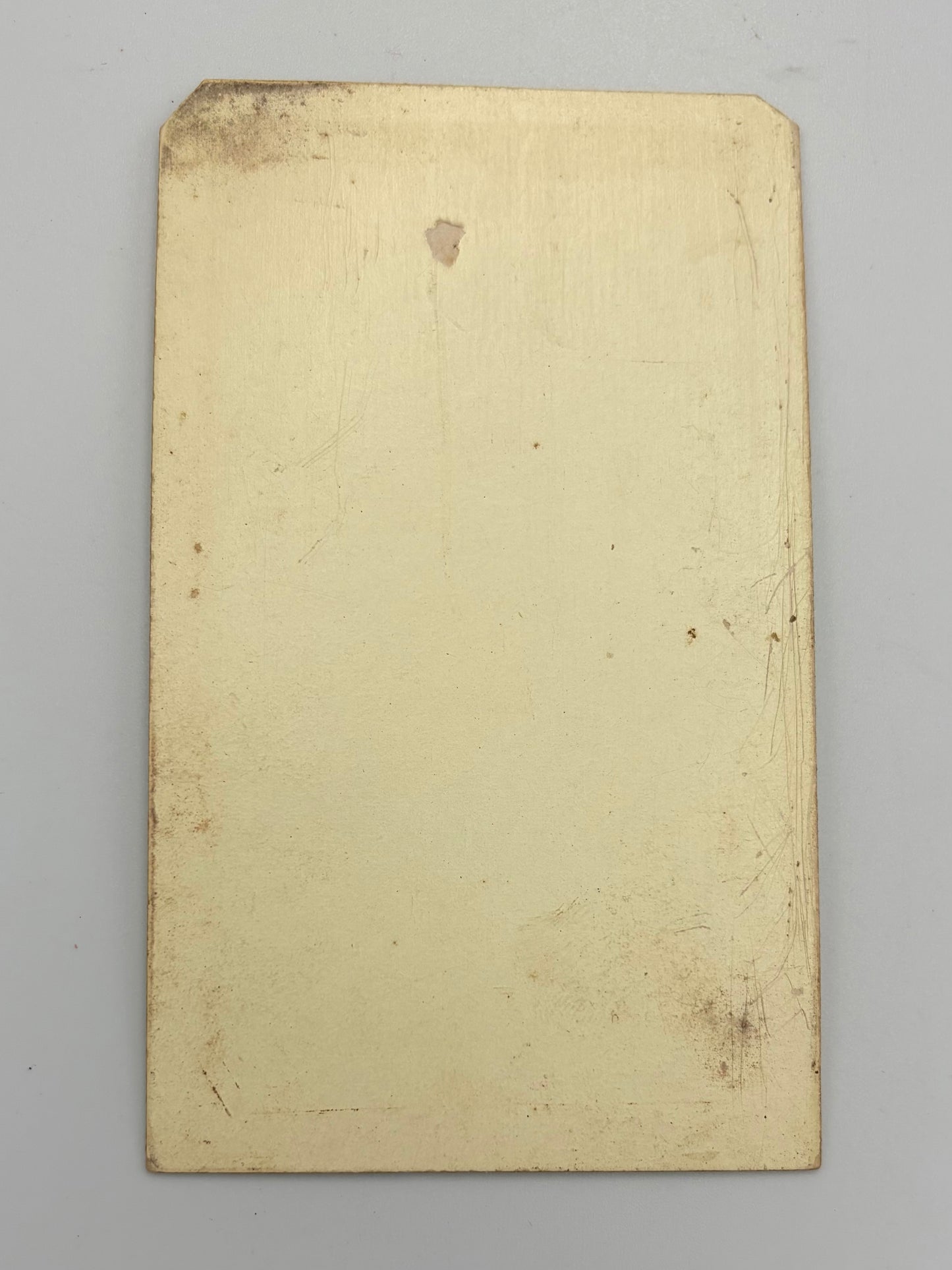 A rectangular, cream-colored card with a slightly worn, vintage finish, photographed flat against a neutral light gray background.