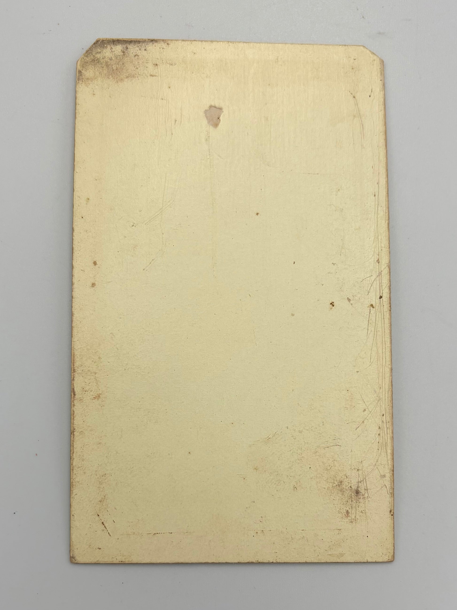 A rectangular, cream-colored card with a slightly worn, vintage finish, photographed flat against a neutral light gray background.
